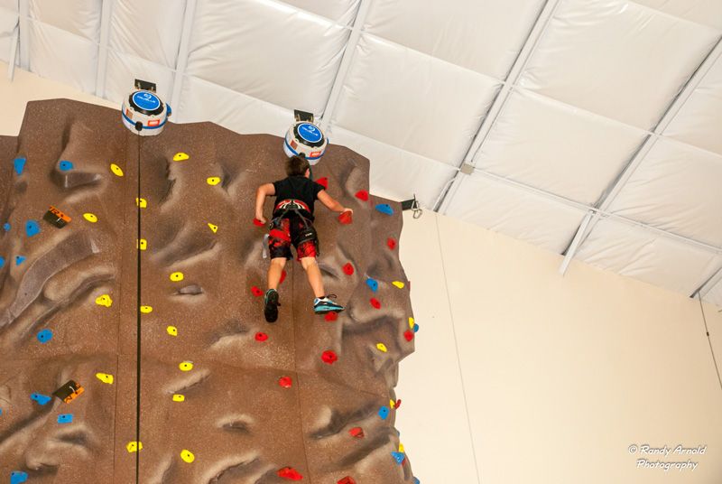 young boy reaching the top of a rock climbing wall